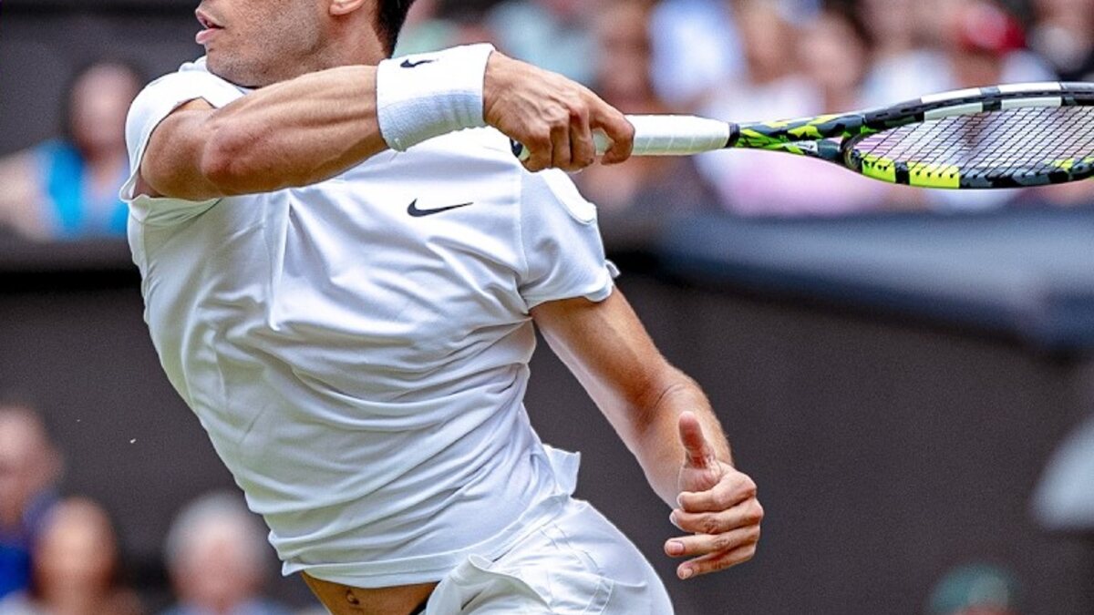 Carlos Alcaraz plays a forehand on a grass tennis court