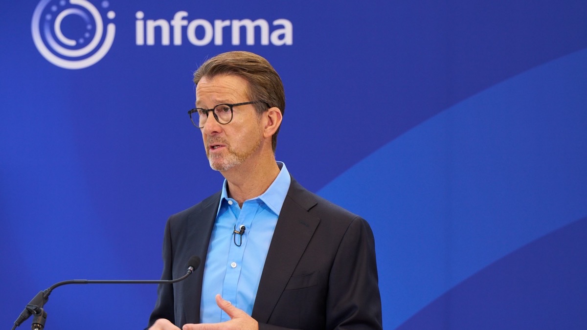 Informa chief executive Stephen Carter speaking in front of the company logo