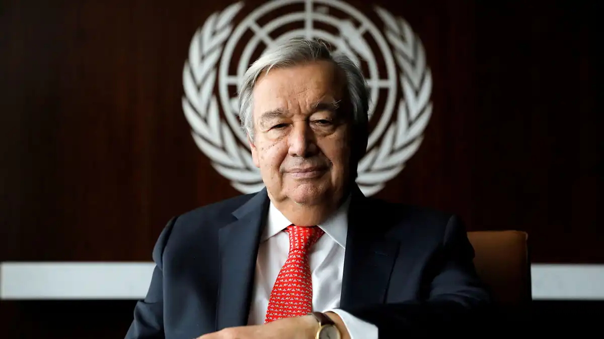 United Nations Secretary-General António Guterres seated beneath the UN emblem